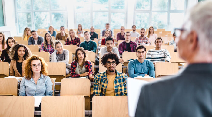 A large group of college students paying attention to their professor during a class.